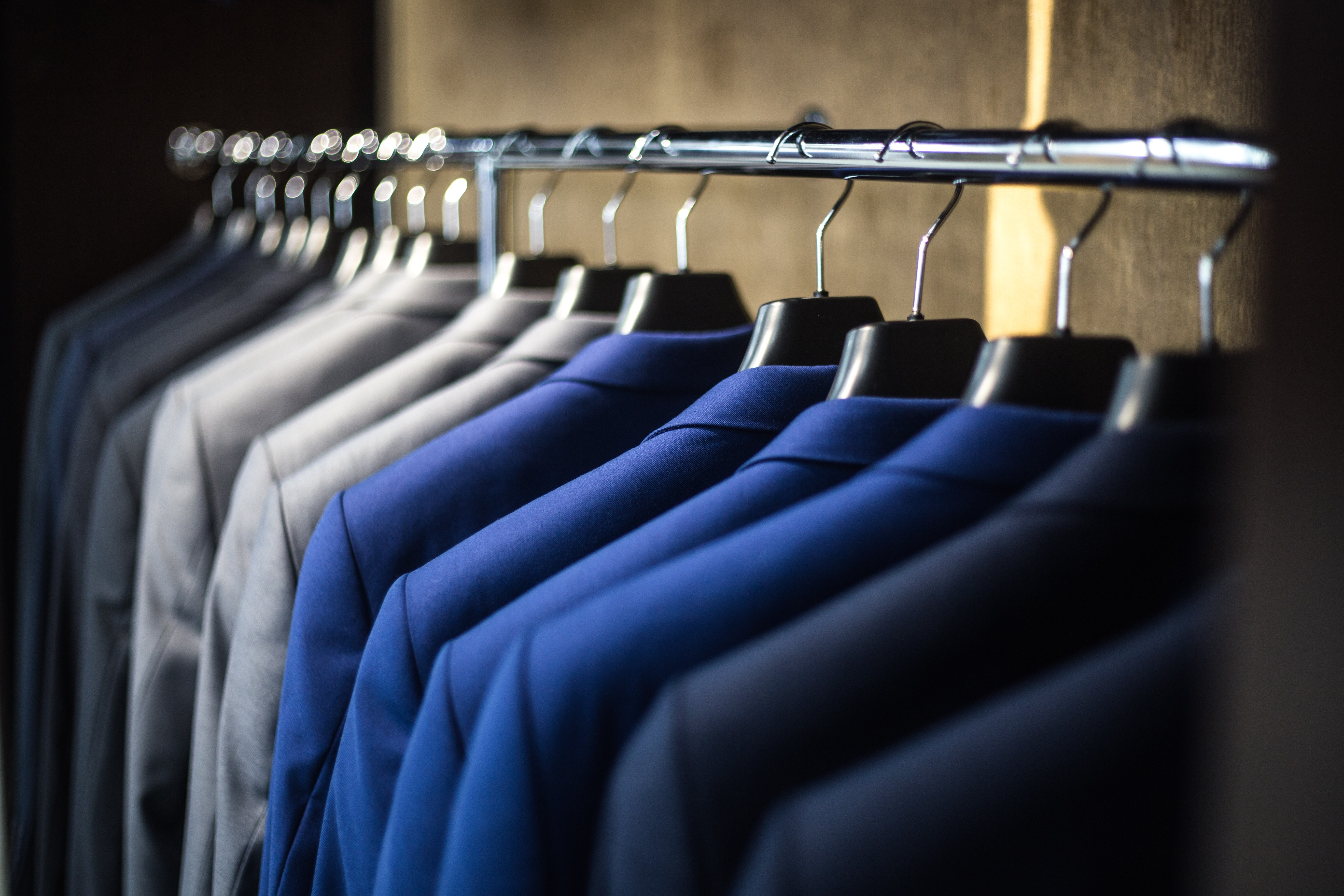 A photo of a rack of suit jackets from dark blue to light gray on Apparel 101 page